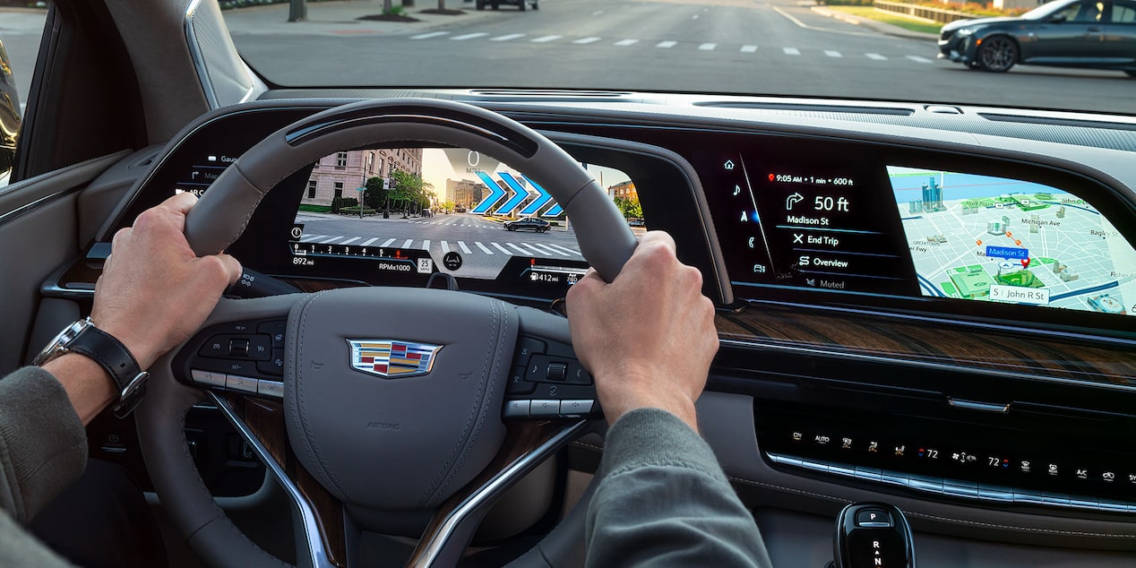 A person holding the steering wheel of the 2024 Cadillac Escalade featuring the augmented reality navigation.