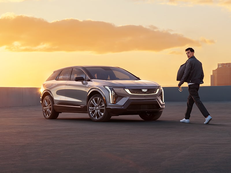 2025 Cadillac OPTIQ electric SUV parked alone outdoors as a person approaches it.