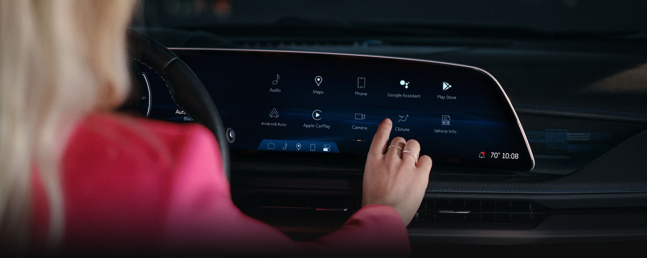 A person pressing the infotainment screen inside the 2025 Cadillac XT4.