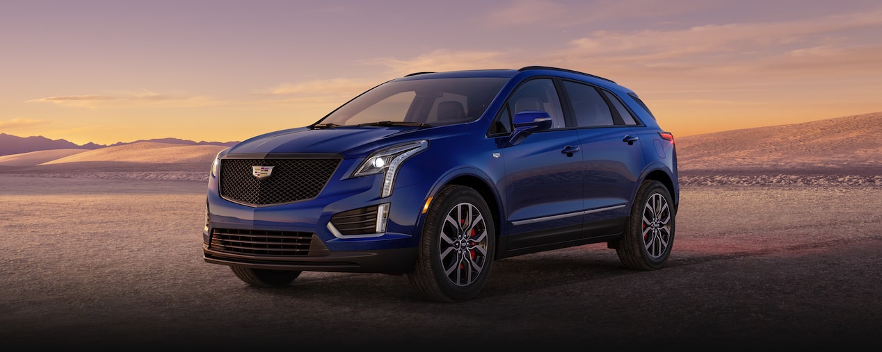 Front-side view of the 2025 Cadillac XT5 luxury SUV parked alone in a sandy environment.