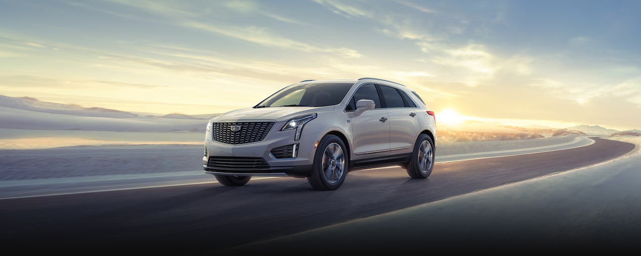 2025 Cadillac XT5 luxury SUV driving alone on a sunny day.