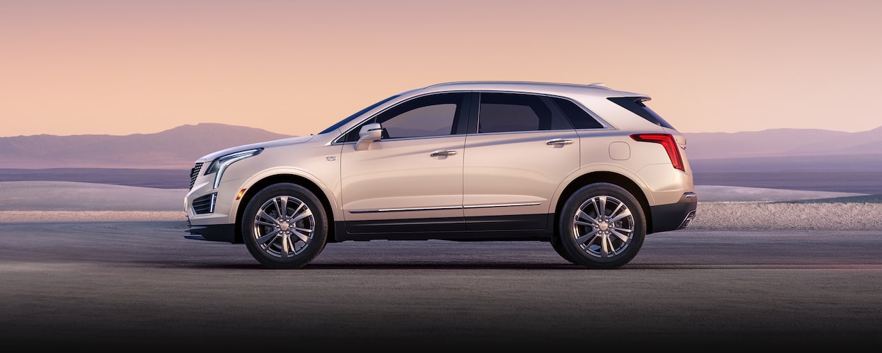 Side view of the 2025 Cadillac XT5 luxury SUV parked near a mountain scenery.