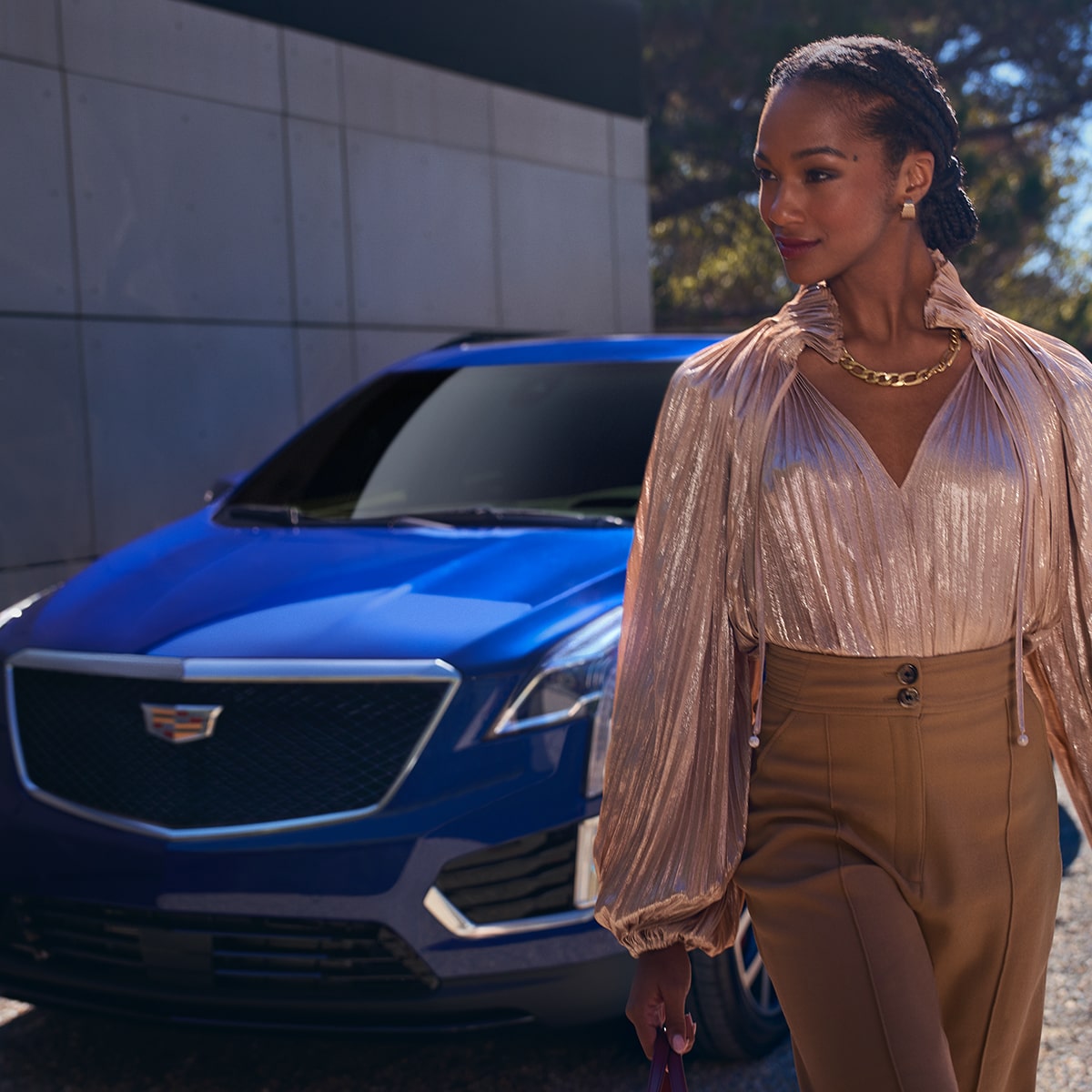 A person passes by a 2025 Cadillac XT5 luxury SUV parked beside a wall.