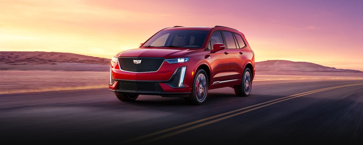 2025 Cadillac XT6 mid-size 7 passenger SUV driving alone on a country road.