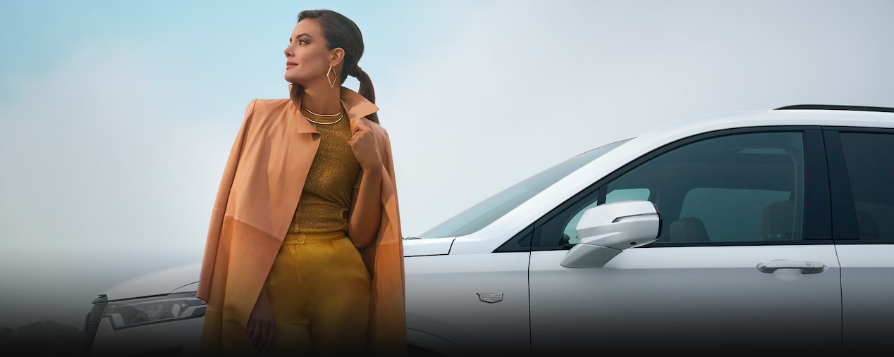 A person standing beside the 2025 Cadillac XT6 mid-size 7 passenger SUV.