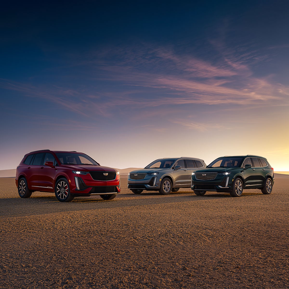 Three 2025 Cadillac XT6 mid-size 7 passenger SUV models parked outdoors during sunset.