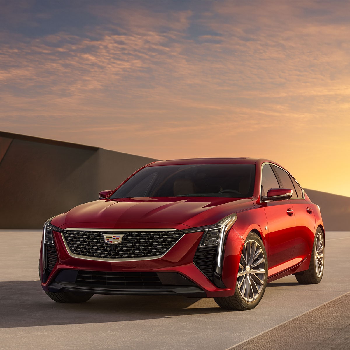 Front-side view of the 2025 Cadillac CT5 sedan driving on a bridge at sunset.