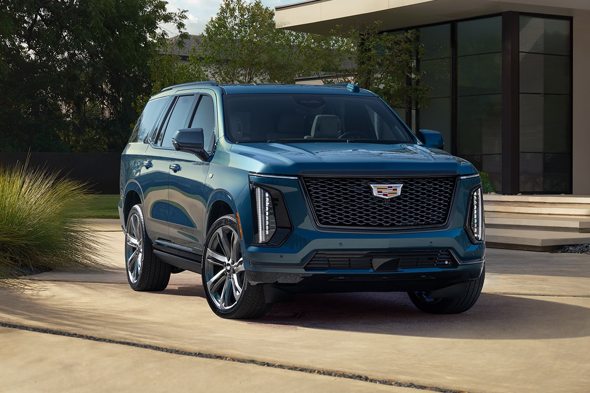 Front-side view of the 2025 Cadillac Escalade parked outside a modern home.