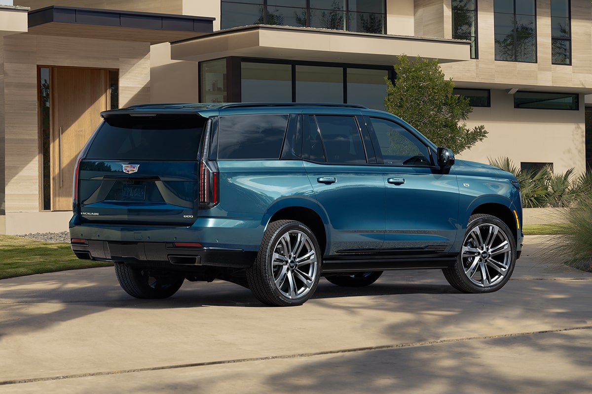 Rear-side view of the 2025 Cadillac Escalade parked outside a modern home.