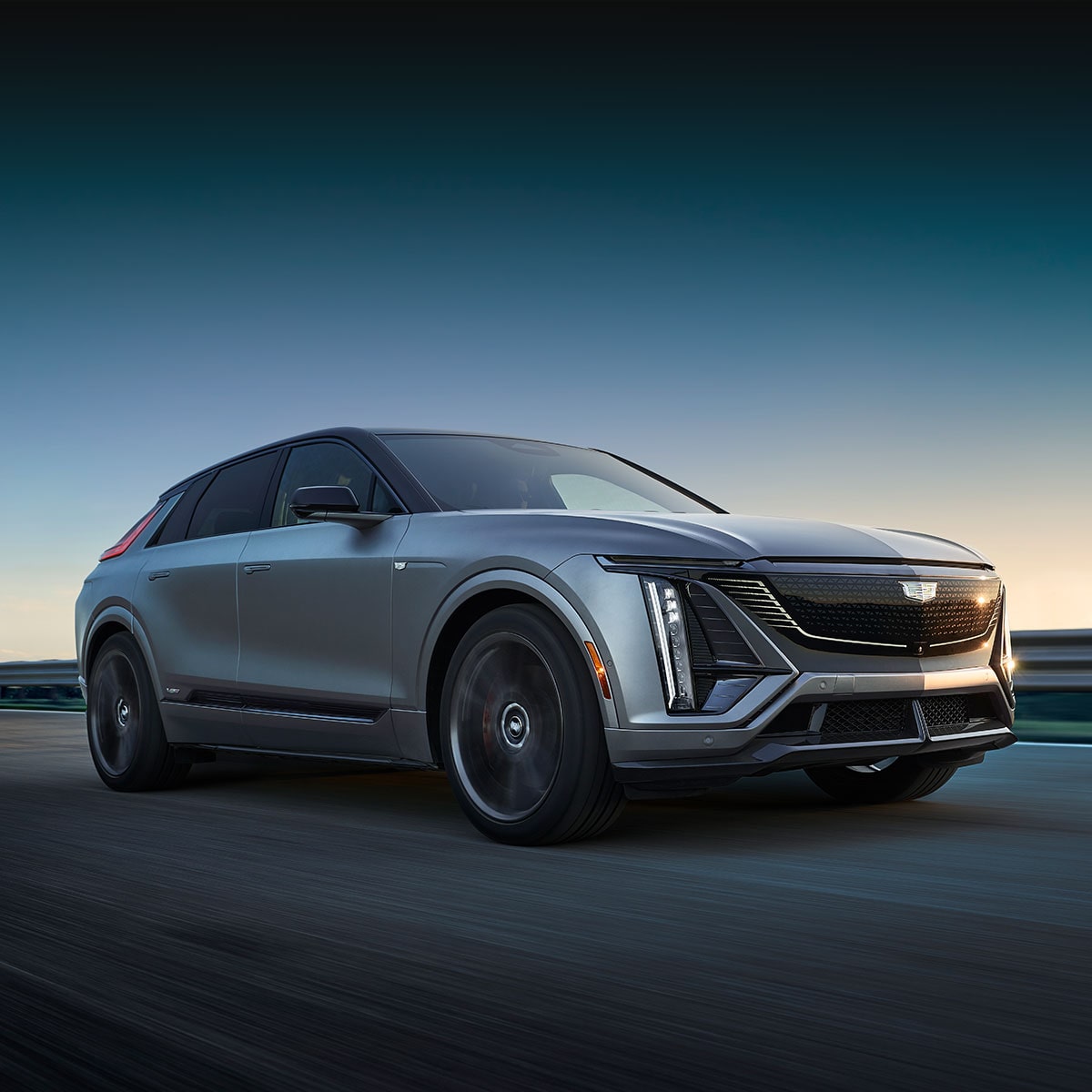 The 2026 Cadillac LYRIQ-V driving fast on the road during sunset.