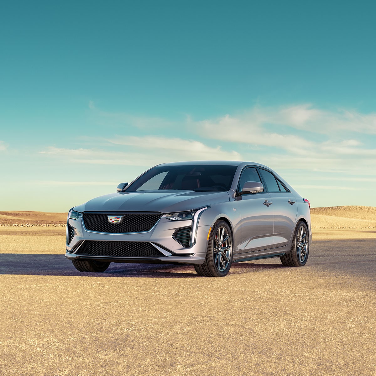 2025 Cadillac CT4 luxury sedan parked on a sandy terrain.