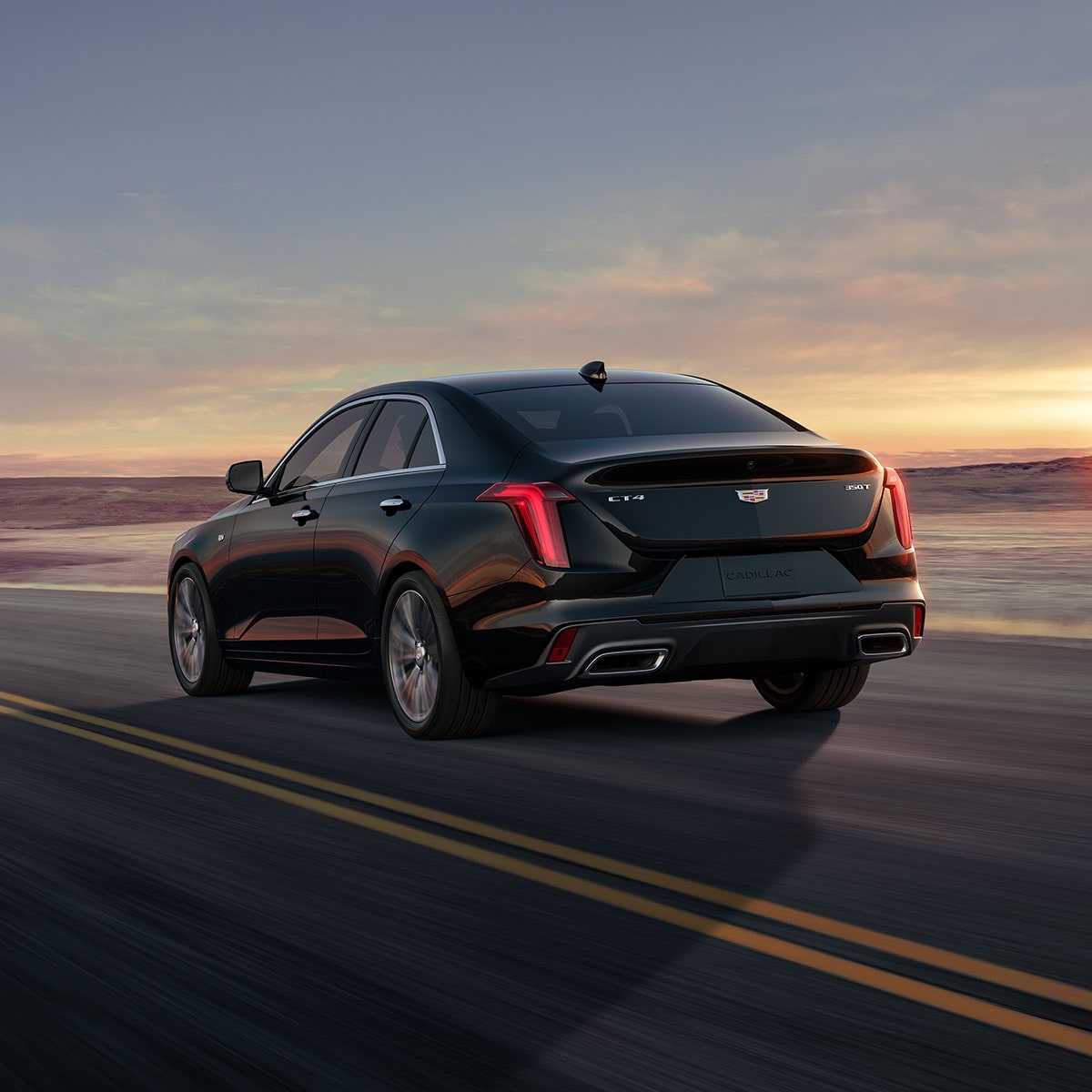 Back-side view of the 2025 Cadillac CT4 luxury sedan driving fast on the road.