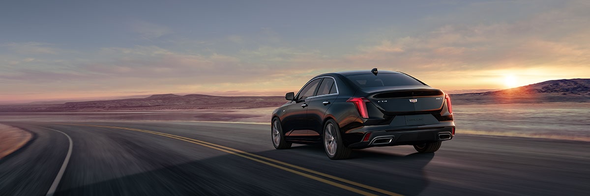 Vue latérale arrière de la berline de luxe Cadillac CT4 2025 qui roule à toute allure sur une route.