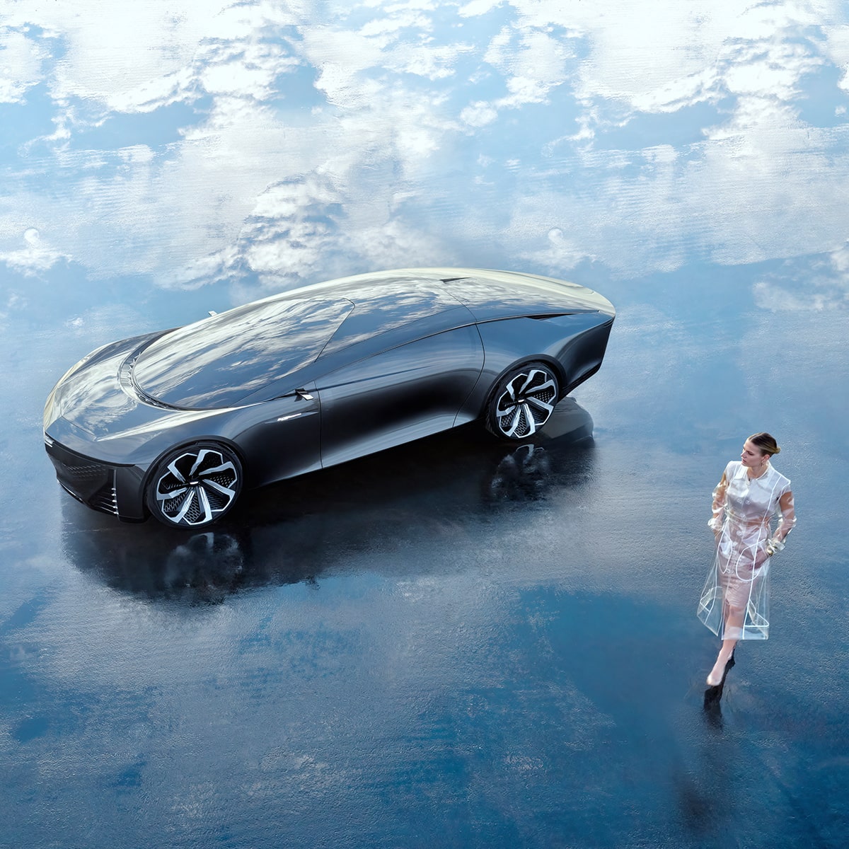 Le véhicule concept Cadillac InnerSpace stationné sur un terrain reflétant un ciel nuageux avec une personne qui passe à côté..