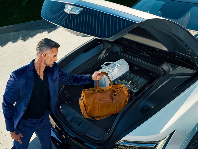 A person stowing his bags on the front storage trunk of his 2025 Cadillac Escalade IQ electric suv.