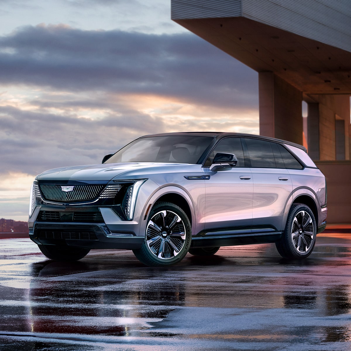 Front-side view of the 2025 Cadillac Escalade IQ electric suv parked on wet flooring during a cloudy weather.