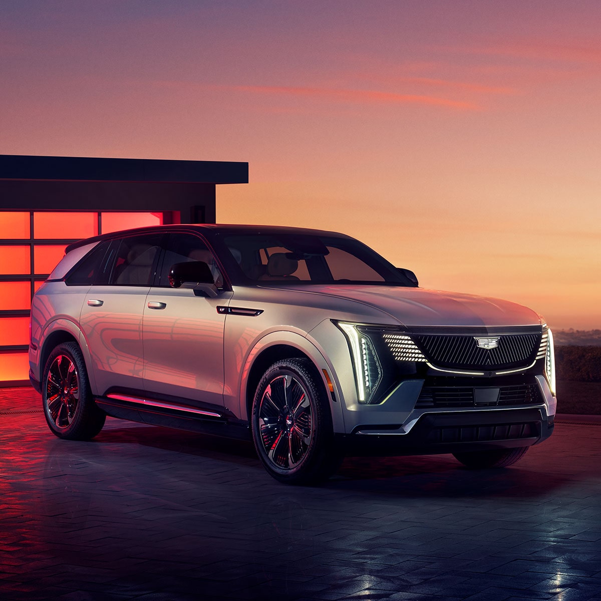 2025 Cadillac Escalade IQ electric suv parked alone outside a modern home during sunset.