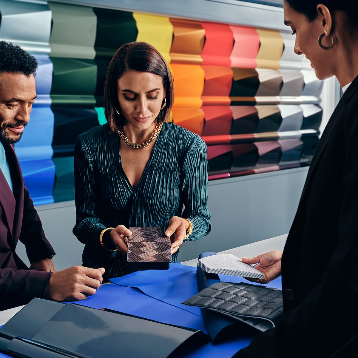 Une représentante commerciale de la berline électrique Cadillac CELESTIQ discute de palettes de couleurs du véhicule avec des clients.