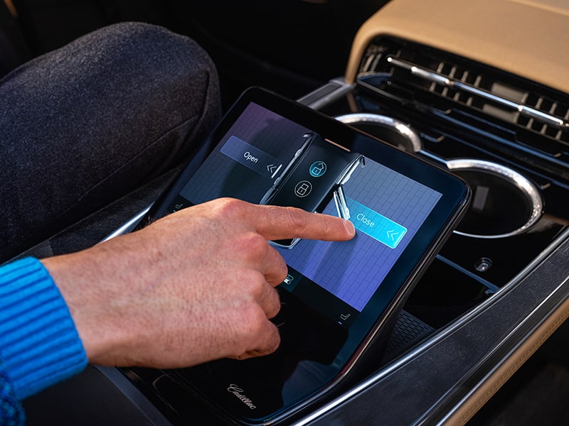 A person from the second row using a touch screen inside the Cadillac Escalade IQ.