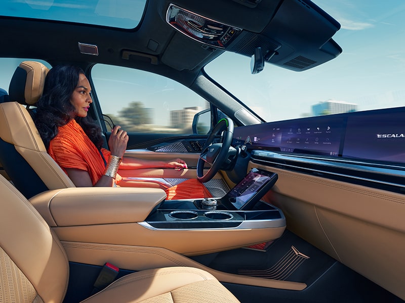 A person smiling while seated at the driver's seat of the Cadillac Escalade IQ.