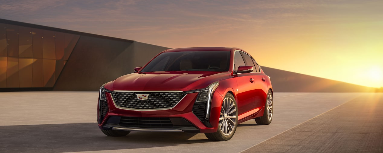 Front-side view of the 2025 Cadillac CT5 sedan driving on a bridge at sunset.