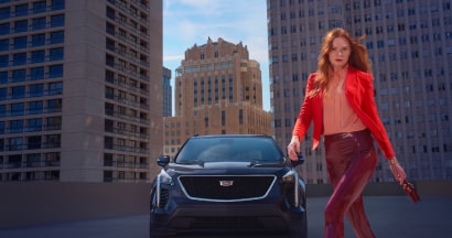 A person on a rooftop passing by a Cadillac vehicle for GM Discount Programs.